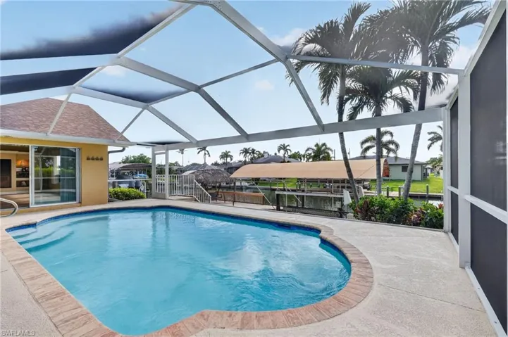 Screened lanai featuring a swimming pool with concrete decking, a brick coping, and a water-facing patio with a white railing