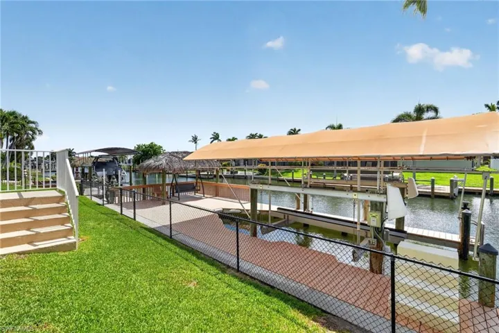 Waterfront property featuring a covered boat lift, an additional boat dock, and a tiki hut structure