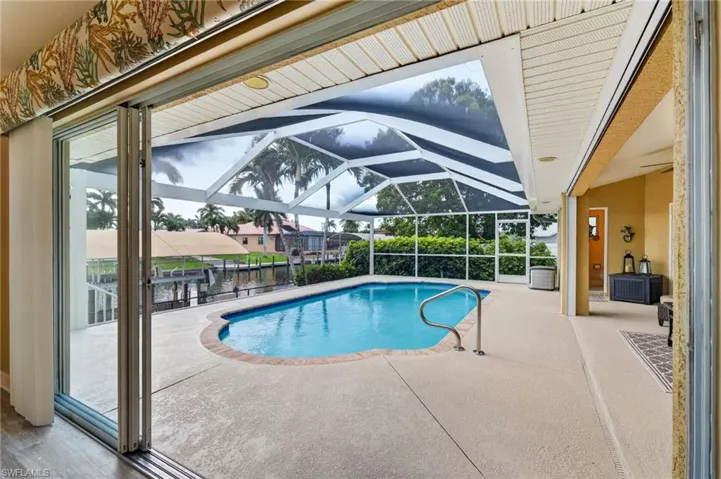Screened lanai with a freeform pool, overlooking a canal with boat docks