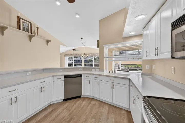 Bright kitchen featuring white cabinetry, light-toned countertops, and wood-finish flooring
