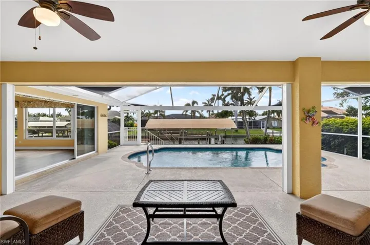 Covered lanai featuring a built-in swimming pool, direct water access with a boat lift, and a screened enclosure