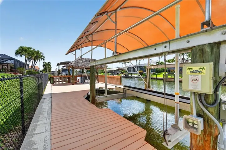 Waterfront dock featuring a covered boat lift, composite decking, and electrical power outlets