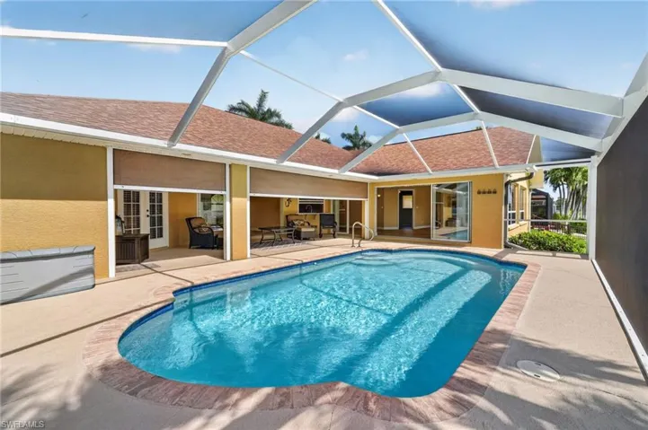 Screened-in pool area featuring a freeform pool with brick coping