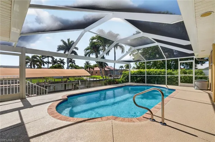 Screened enclosure featuring a swimming pool with a curved edge and brick coping