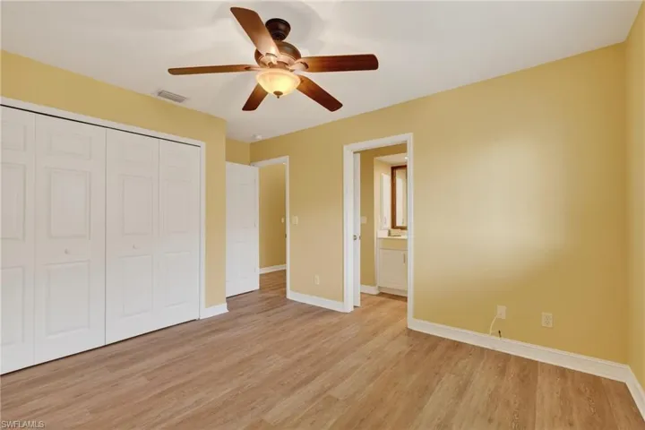Spacious room featuring wood-finish flooring, light yellow walls, and a ceiling fan with integrated lighting