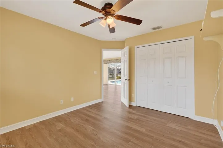 Interior room featuring wood-finish flooring, a ceiling fan with integrated lighting, and bi-fold closet doors