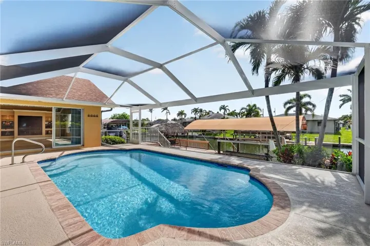 Screened outdoor swimming pool with a brick coping, surrounded by a concrete deck