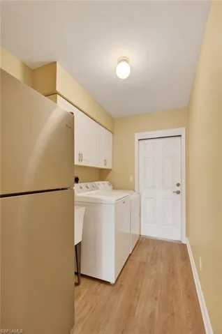 Dedicated utility space featuring wood-finish flooring, white cabinetry, and a utility sink