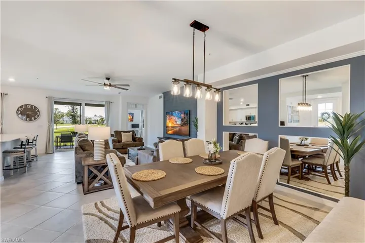 Tiled dining space featuring ceiling fan with notable chandelier and a wealth of natural light