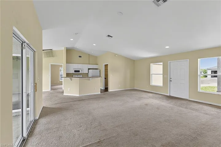 Spacious interior featuring a vaulted ceiling and recessed lighting