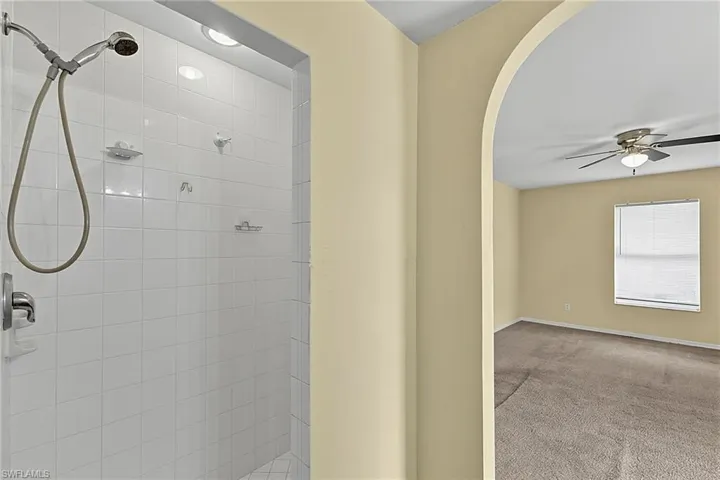White tiled shower stall with recessed lighting and chrome fixtures