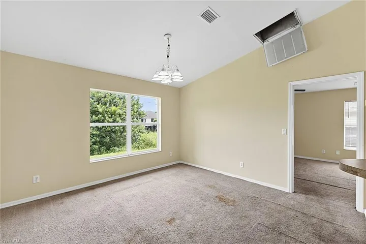 Spacious interior with vaulted ceilings, a large window providing abundant natural light, and a decorative chandelier