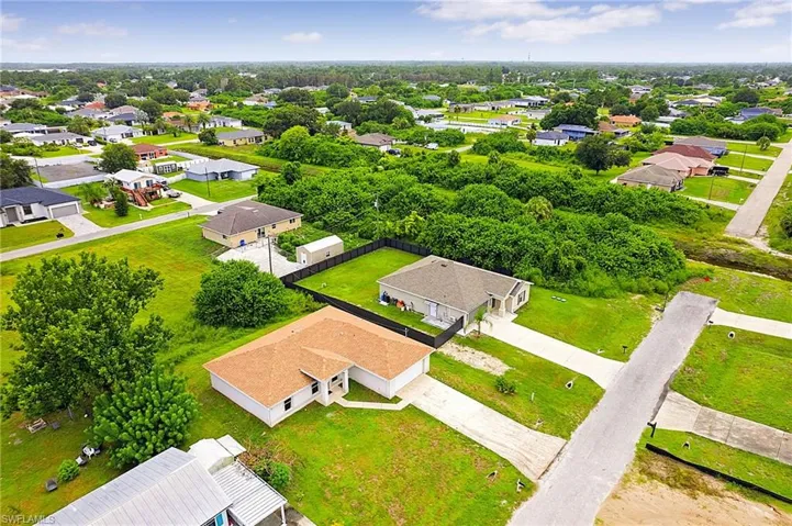 Aerial perspective showcasing a residential neighborhood with single-story homes, expansive green lawns, and mature trees