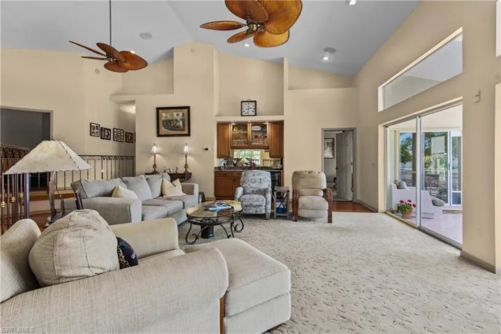 Carpeted living room featuring high vaulted ceiling and ceiling fan