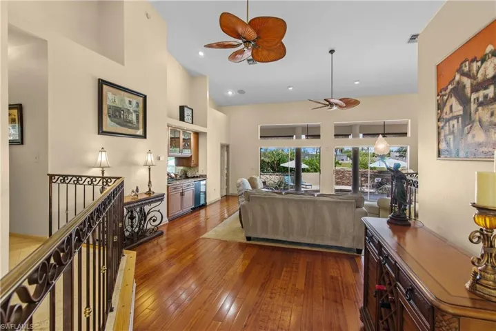 Living room featuring a high ceiling, dark wood-type flooring, and ceiling fan