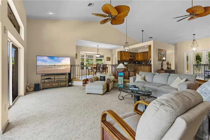 Carpeted living room with high vaulted ceiling and ceiling fan