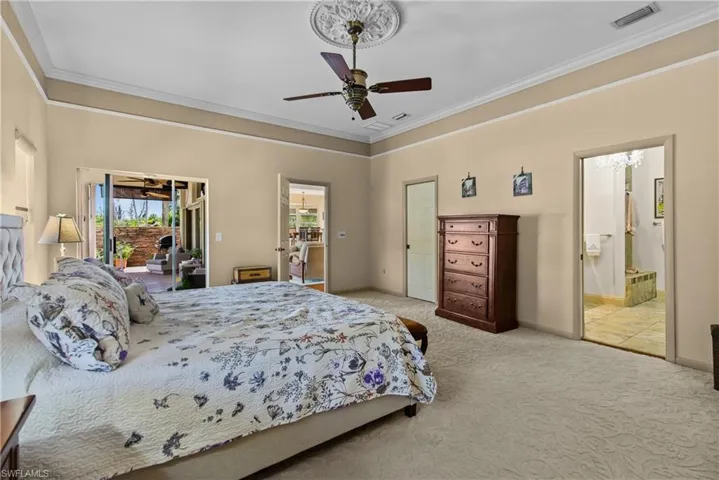 Huge Main Bedroom featuring crown molding, ensuite bath, access to exterior and ceiling fan
