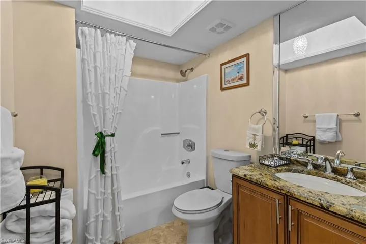 Full guest bathroom featuring tile flooring, toilet, shower / bath combo with shower curtain, and vanity