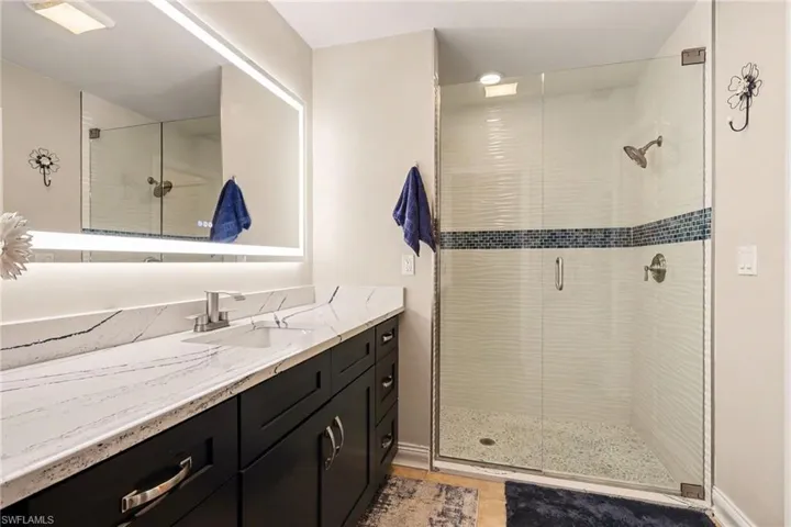 This bathroom remodel is just as impressive as the kitchen! A lustrous & modern backlit mirror & lavish Quartz counters
