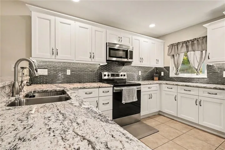Gorgeous granite counter tops and a sleek steel blue glass tile backsplash