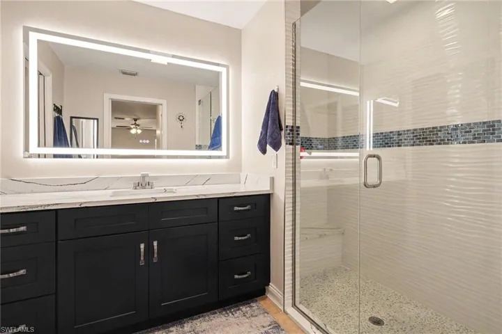 Check out the cool "wavy" white tiles with a glistening glass tile inlay in the shower
