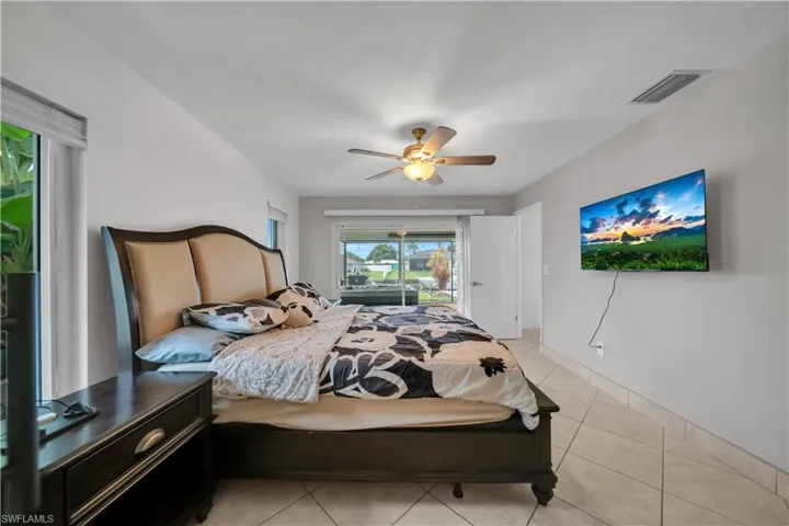 Bedroom featuring access to outside, light tile patterned flooring, and a ceiling fan