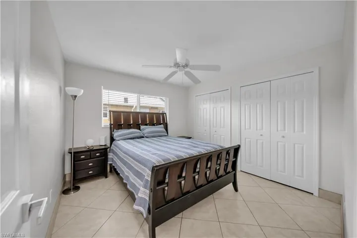 Bedroom with light tile patterned floors, two closets, and a ceiling fan