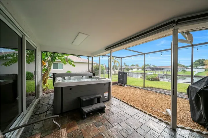 Sunroom featuring plenty of natural light, a jacuzzi, a residential view, and a water view