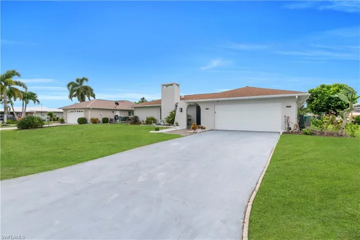 Ranch-style home featuring concrete driveway, a front yard, an attached garage, stucco siding, and a chimney