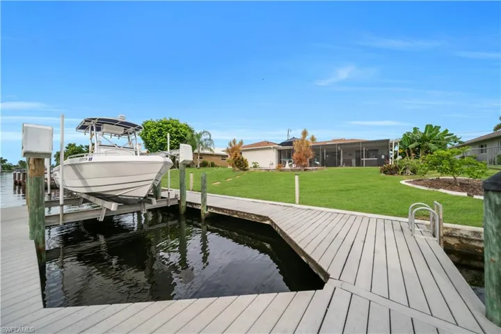 Dock with boat lift, a yard, and a water view
