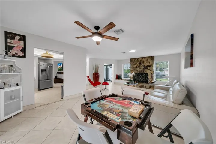 Dining area with light tile patterned floors, a ceiling fan, and a fireplace