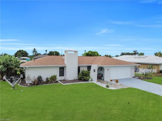 Single story home with driveway, a front yard, stucco siding, a garage, and a chimney