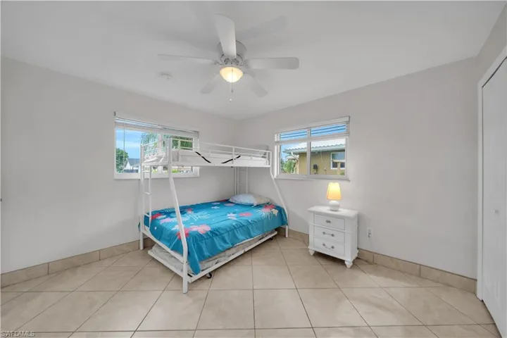 Bedroom with light tile patterned flooring, multiple windows, and a ceiling fan
