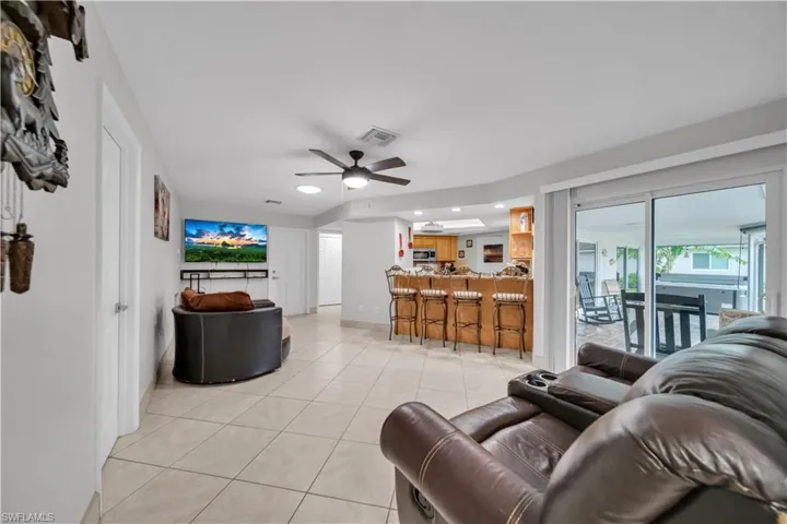 Living room with light tile patterned floors, a ceiling fan, and recessed lighting