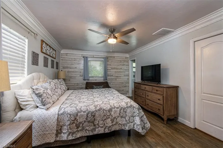 Bedroom featuring multiple windows, crown molding, ceiling fan, and dark wood-type flooring