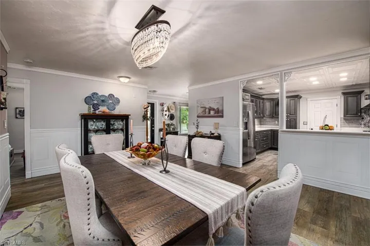 Dining area with crown molding, sink, dark hardwood / wood-style floors, and a notable chandelier