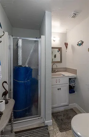 Bathroom with tile patterned flooring, vanity, a shower with shower door, and toilet