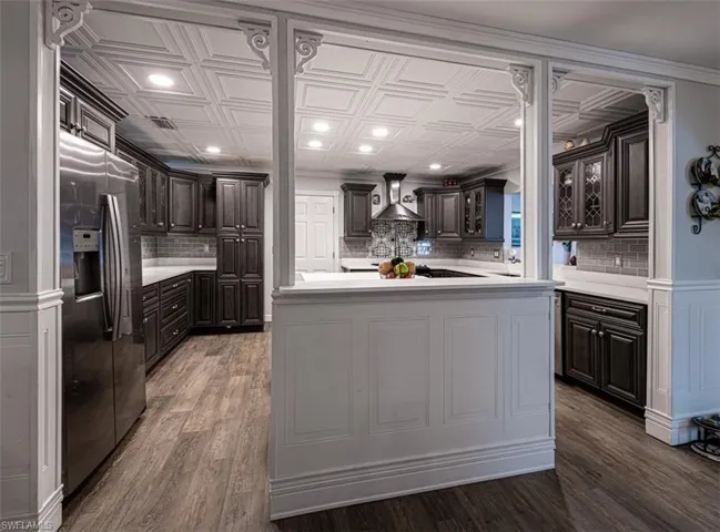 Kitchen featuring backsplash, dark hardwood / wood-style floors, stainless steel fridge, a kitchen island, and dark brown cabinetry
