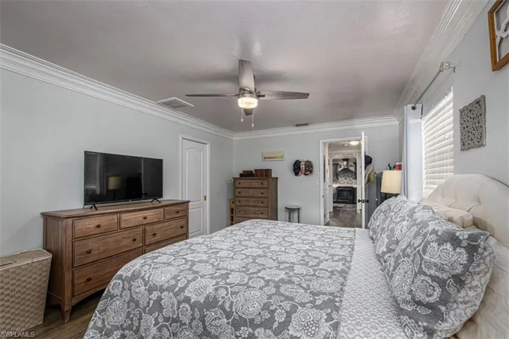Bedroom featuring wood-type flooring, a closet, ceiling fan, and crown molding