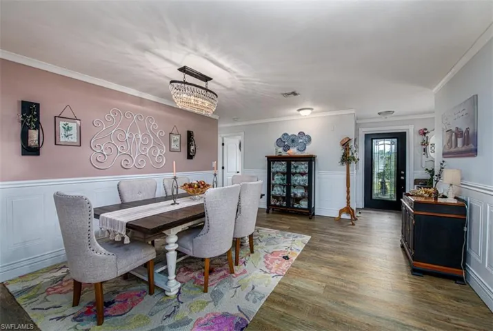 Dining space with dark hardwood / wood-style flooring, ornamental molding, and an inviting chandelier