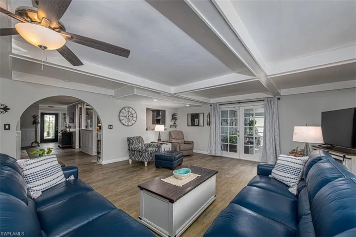 Living room with hardwood / wood-style floors, ceiling fan, beam ceiling, and french doors