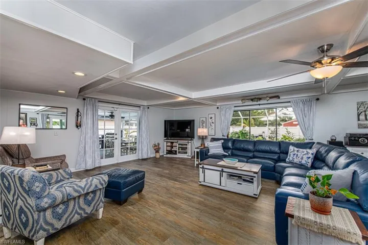 Living room featuring dark wood-type flooring, coffered ceiling, french doors, ceiling fan, and beamed ceiling