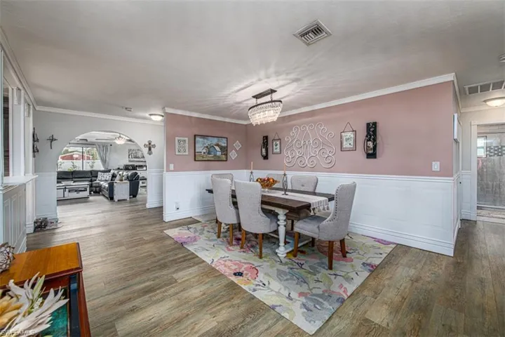Dining area with ornamental molding, ceiling fan with notable chandelier, and hardwood / wood-style flooring