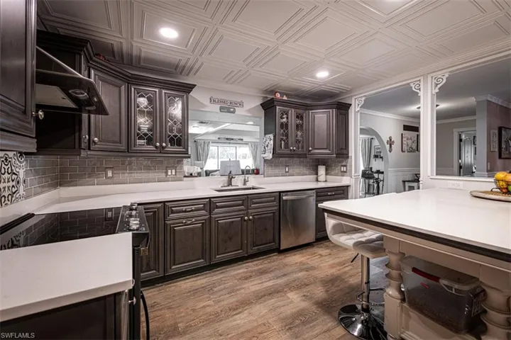 Kitchen featuring sink, stainless steel dishwasher, crown molding, wood-type flooring, and dark brown cabinets