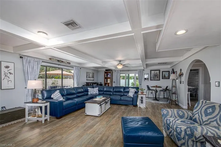 Living room featuring beamed ceiling, dark hardwood / wood-style floors, a wealth of natural light, and coffered ceiling