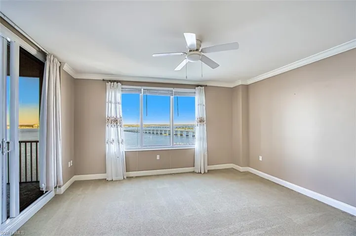 Carpeted spare room with a water view, ceiling fan, and crown molding