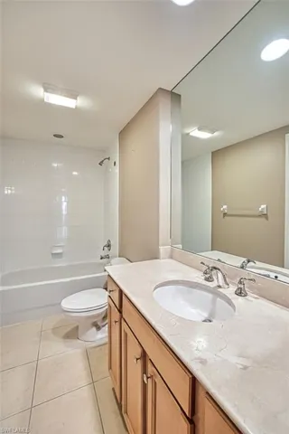 Full bathroom featuring tile patterned floors, vanity, tiled shower / bath combo, and toilet