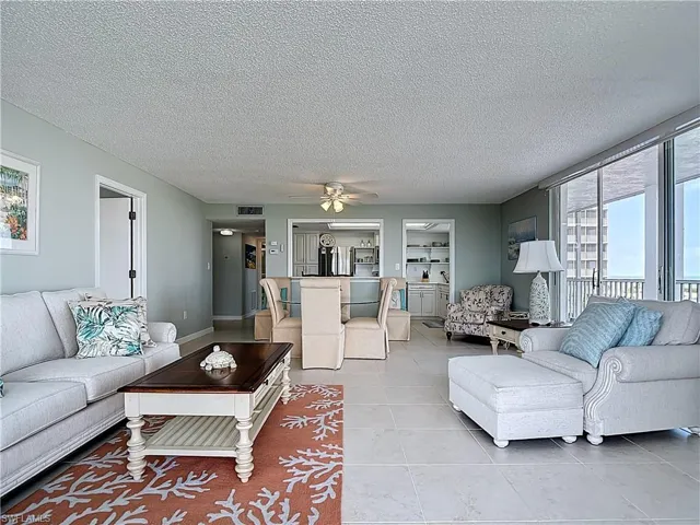 Living room with a textured ceiling, ceiling fan, and light tile patterned floors
