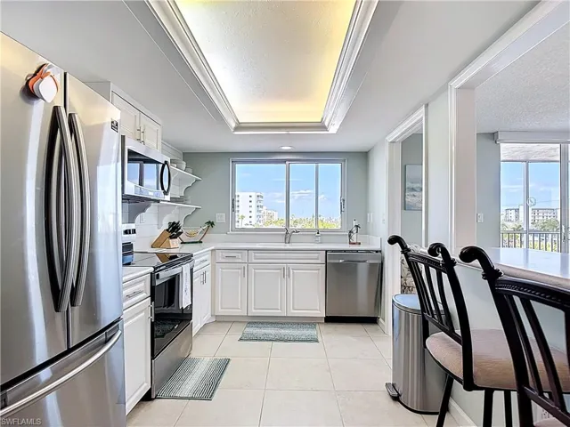 Kitchen featuring stainless steel appliances, light countertops, white cabinetry, light tile patterned flooring, and a textured ceiling