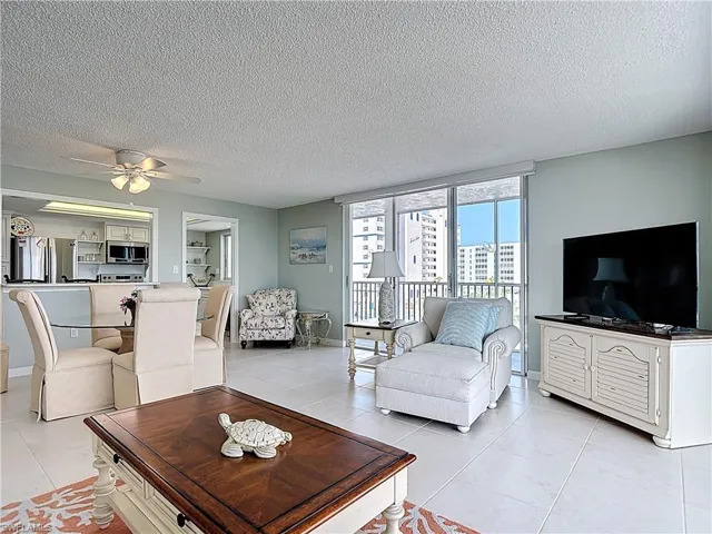 Living room featuring a textured ceiling, a ceiling fan, and light tile patterned floors